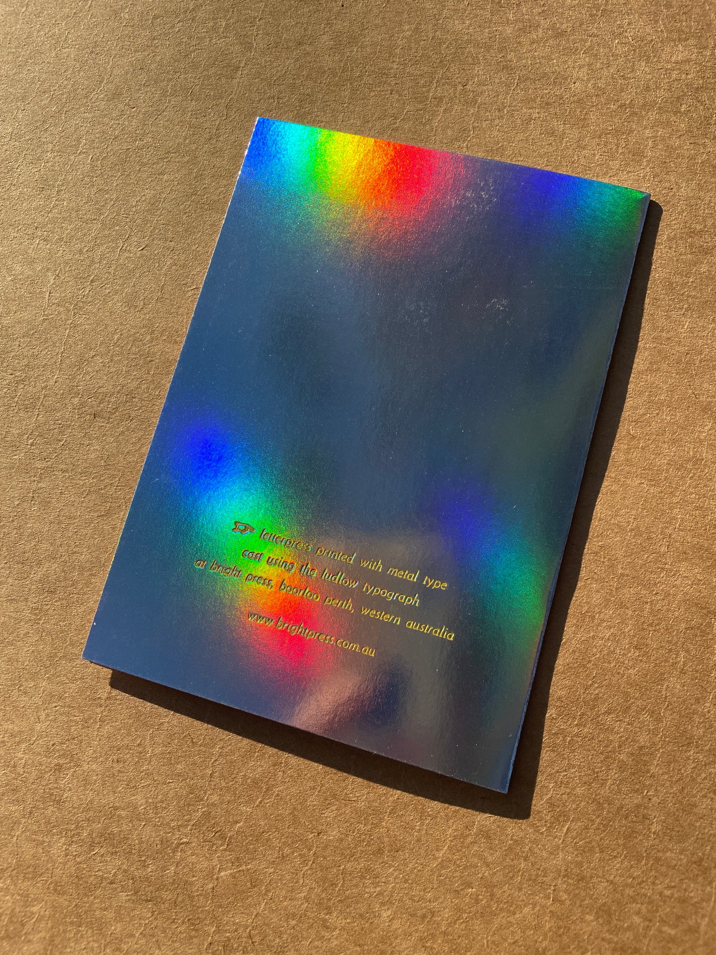 Back of rainbow holographic greeting card on a brown surface