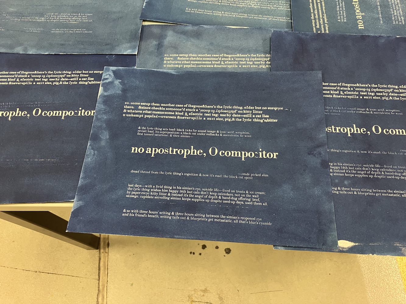From Chris Arnold's work - Collection of cyanotype printed sheets with text on a wooden surface