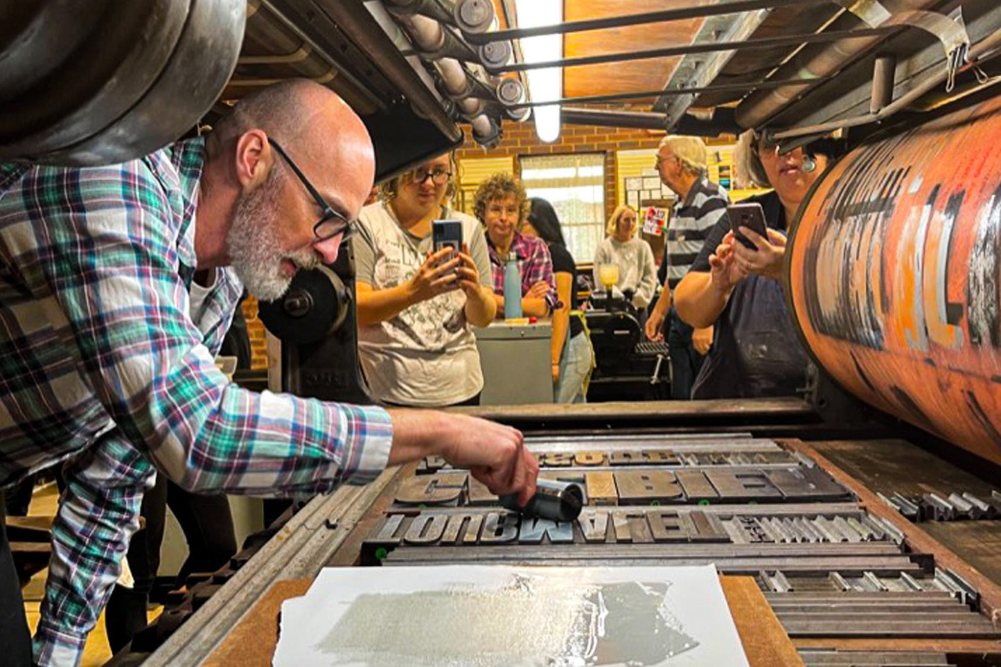 Phil Gambrill inking up in a printing forme of wood type in the belly of a quad crown Miehle press. 