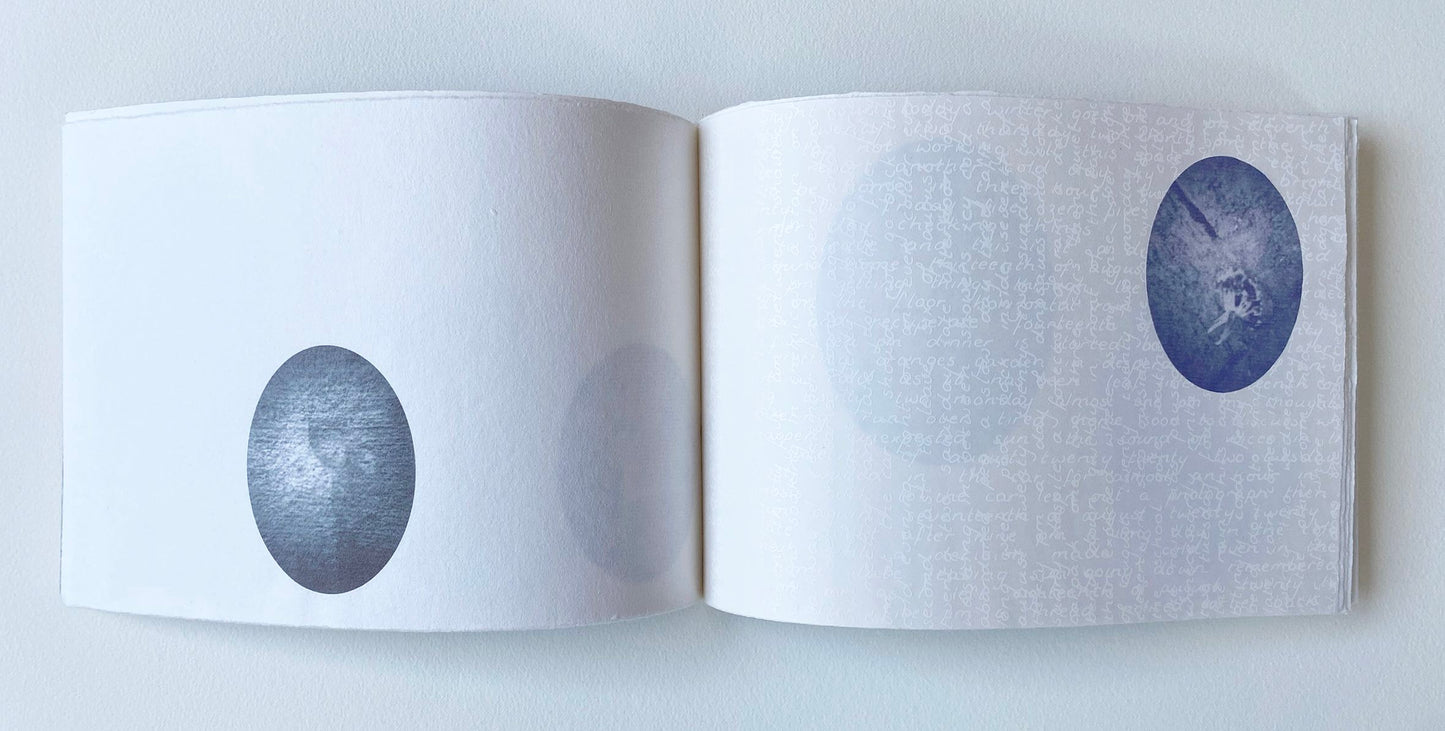 One of Vanessa Wallace's work - Open book with two circular prints surrounded by subtle white text on white paper on a white background