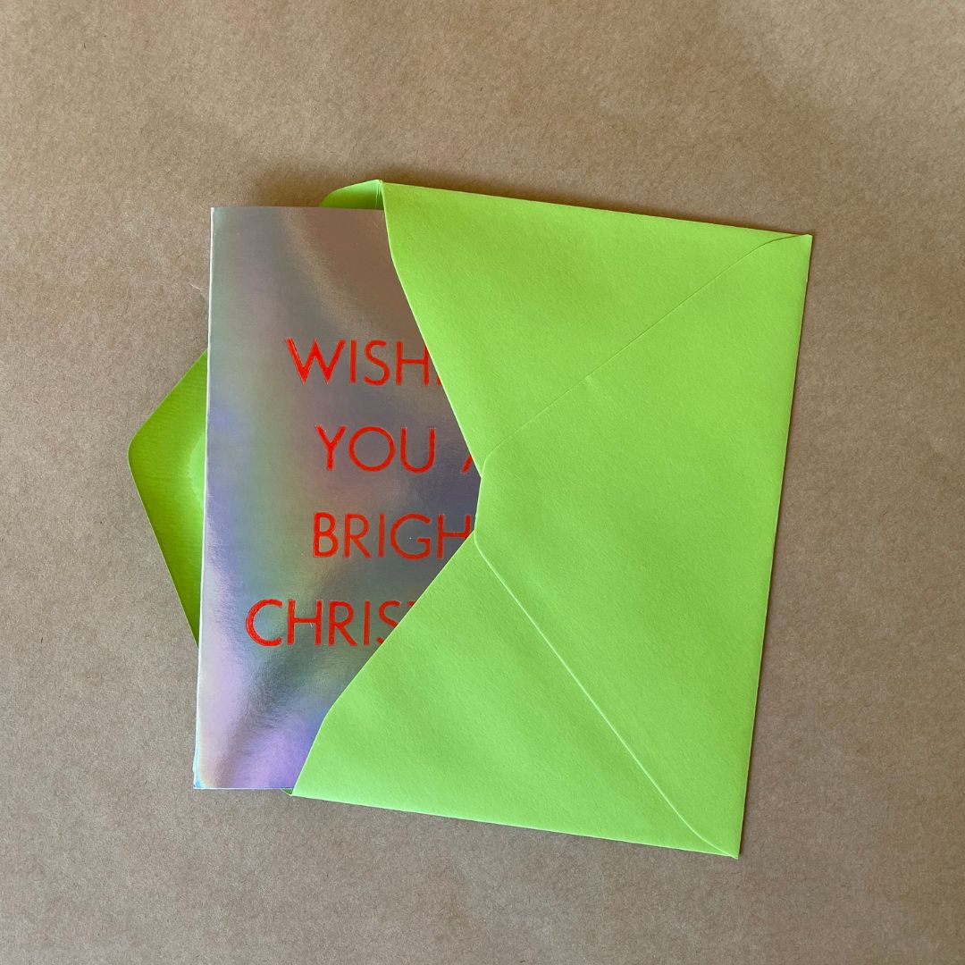 Wishing You A Bright Christmas Card peeking out from its lime green coloured envelope