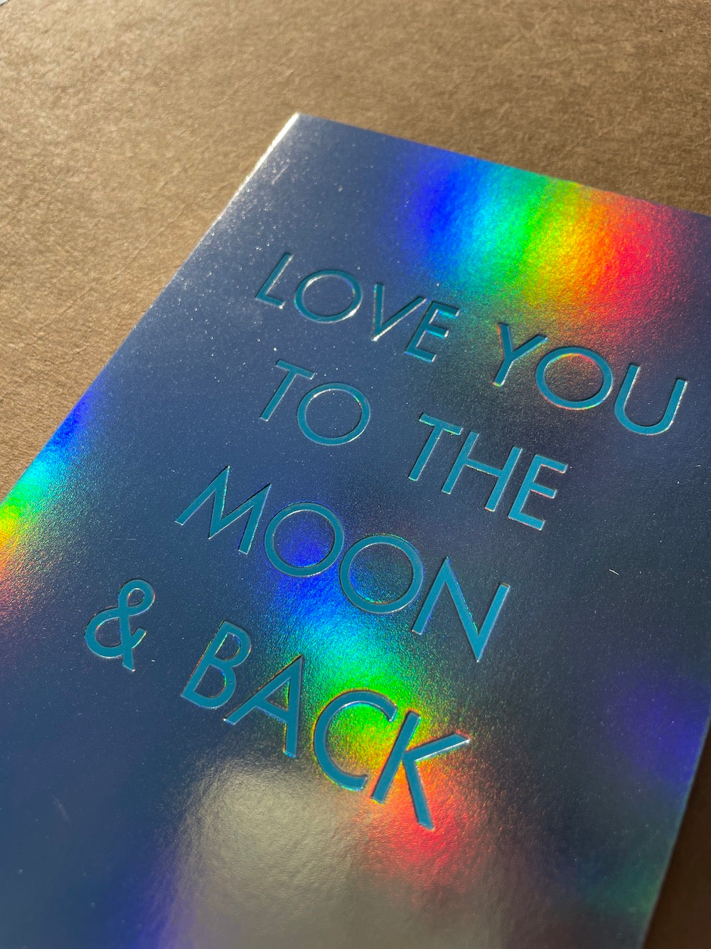 Close up of rainbow holographic foil card with 'Love You to the Moon & Back' text.