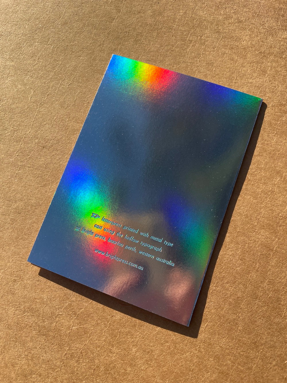 Back of rainbow holographic foil card on a brown textured surface