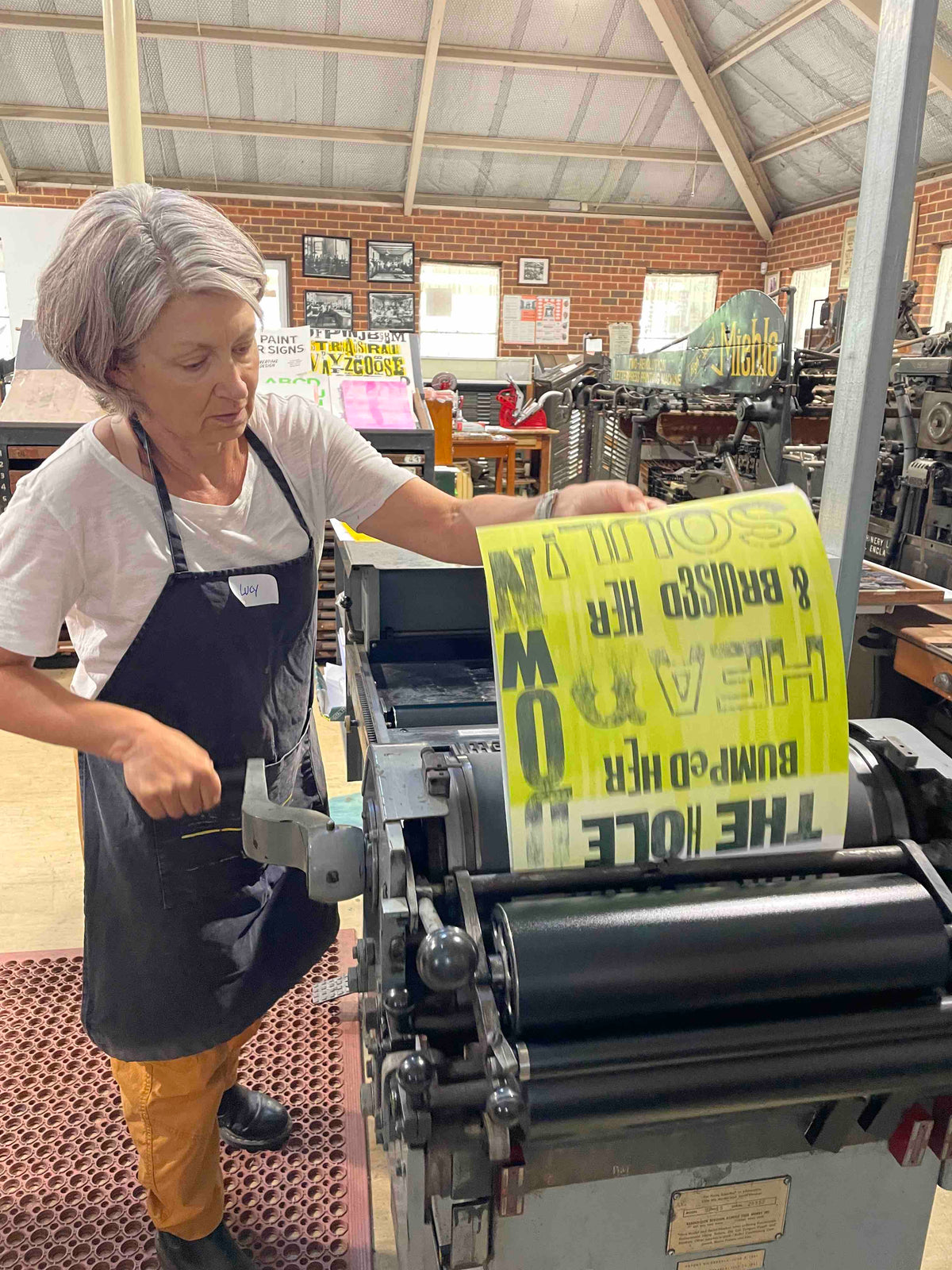 A participant pull a print of their poster on the Vandercook press.