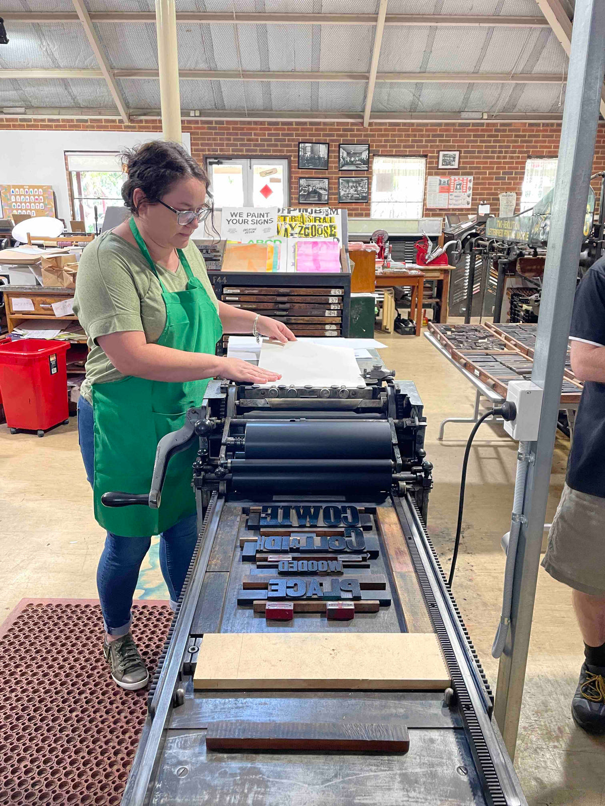 A participant aligning their paper on the feed table in preparation to pull a print.