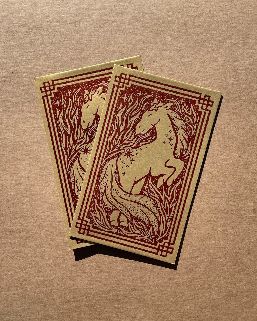 Two envelopes with horse designs on a brown surface