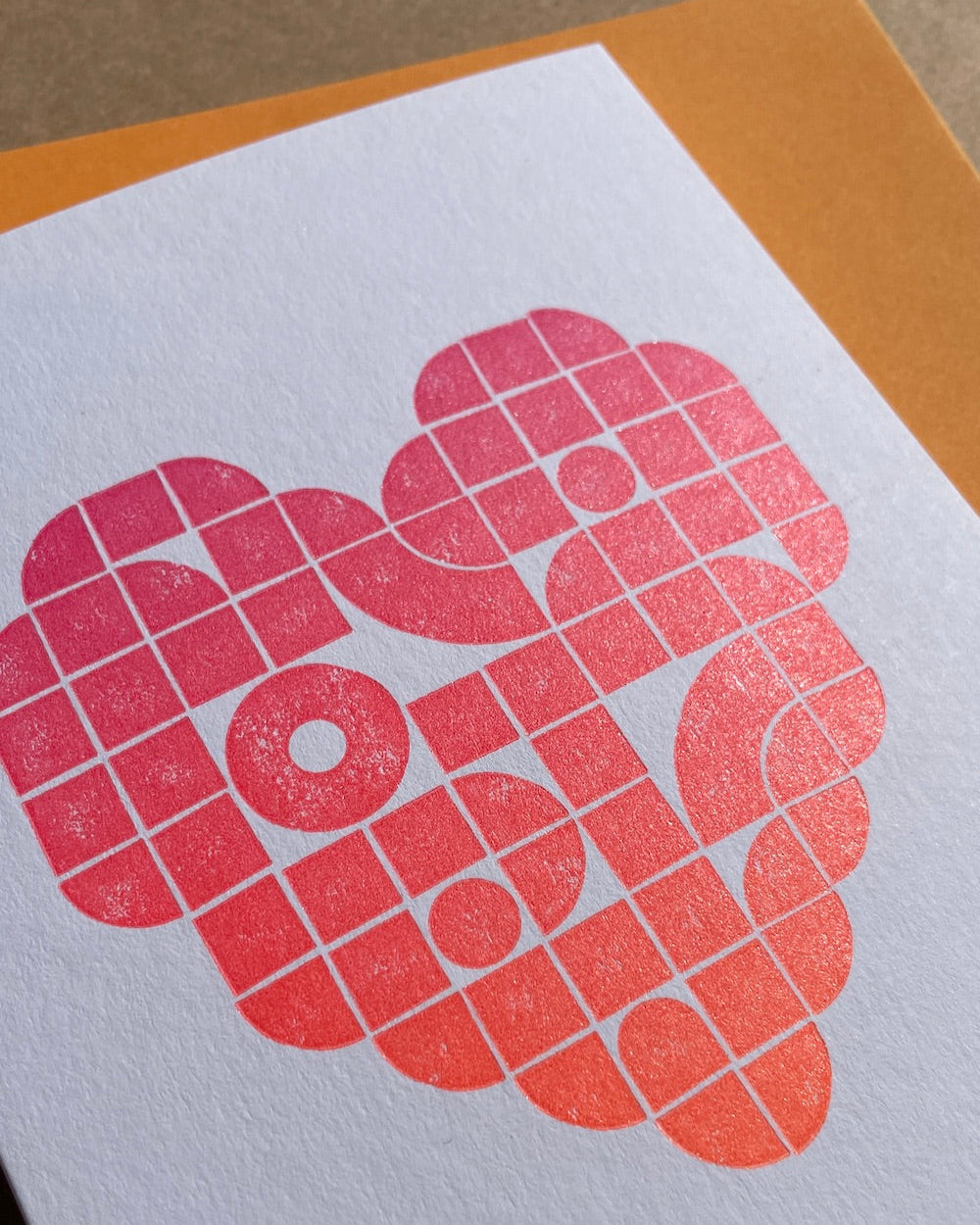 Close up of the card, showing off the gradient colours. In the background is an orange envelope.