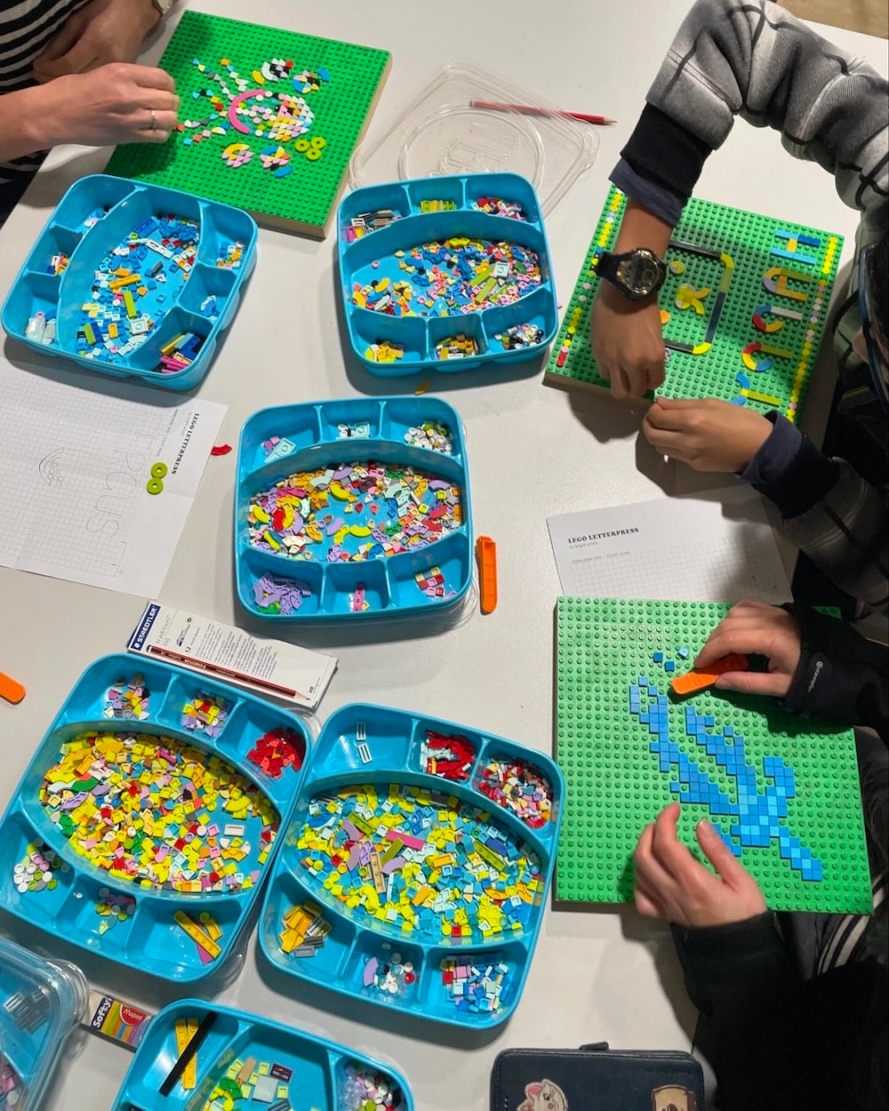 Bird's eye view of a group of workshoppers using lego tiles and creating designs with lego base plates