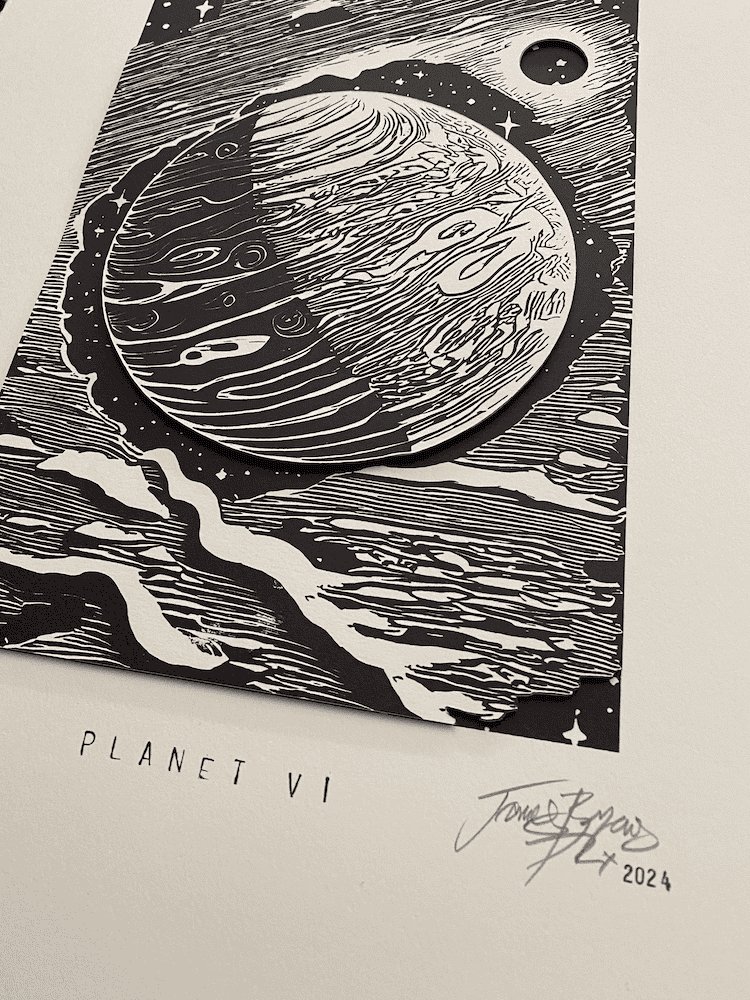 Close up of a black and white print of a planet with 'Planet VI' text and signature by P. James Bryans